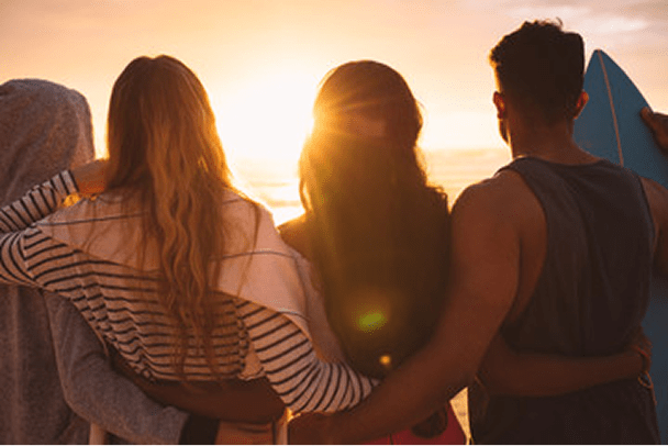 男女が肩を組んで夕陽を見ています