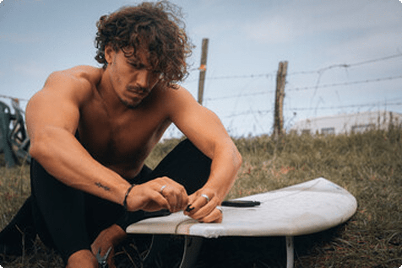 男性がサーフボードをメンテナンスしている